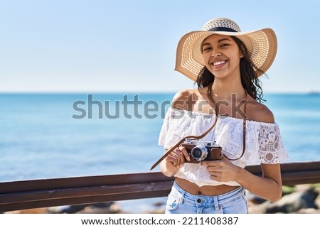 Young african american woman tourist smiling confident using camera at seaside