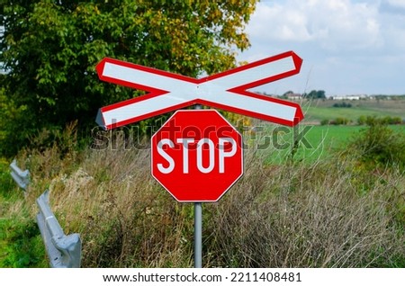 Lonely railway stop sign with cross in the day light
