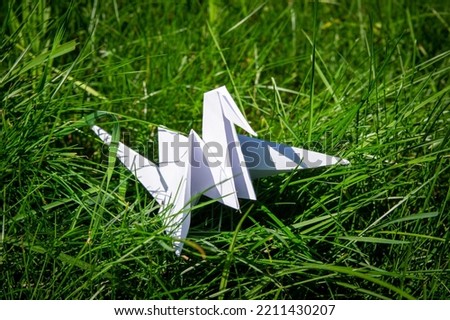 Japanese folded Origami cranes on fresh grass. Hundreds handmade paper birds on green field with copy space. 1000 thousand crane tsuru sculpture topic. Symbol of peace, faith, health, wishes and hope 