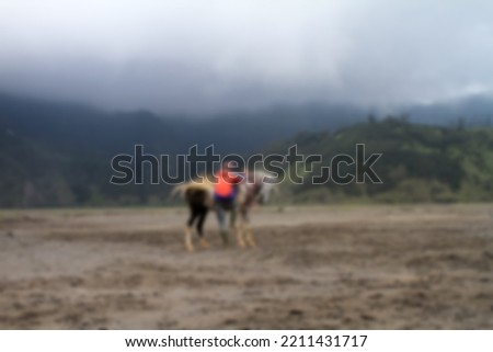 blurred background of a horseman and his strong horse. being in the bromo desert