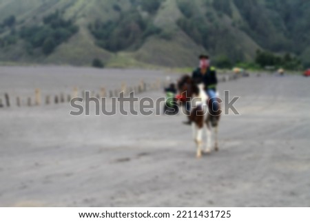 blurred background of a horseman and his strong horse. being in the bromo desert