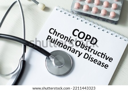 On a white background pills, stethoscope and text COPD Chronic Obstructive Pulmonary Disease. Medical concept Royalty-Free Stock Photo #2211443323