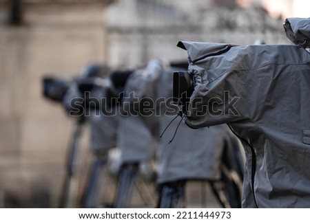 Television live broadcasting production professional cameras on tripod with rain covers on them prepared to broadcast an event. Royalty-Free Stock Photo #2211444973