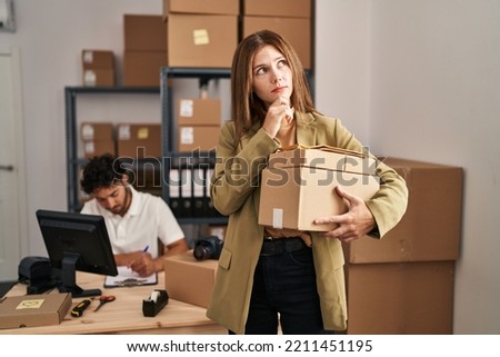 Young two people working at small business ecommerce serious face thinking about question with hand on chin, thoughtful about confusing idea 
