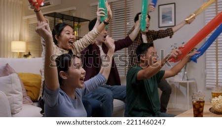 Group of young adult friend man and woman asia people sit at sofa couch joy night party fun game FIFA world cup live TV at home eat snack bowl drink beer bottle glass jump mad happy win exult face Royalty-Free Stock Photo #2211460247