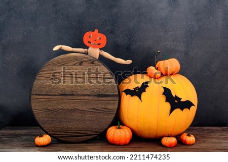 Wood round sign Halloween mockup with funny wood people and many pumpkins, bats on old wooden table by black wall. Celebrating Halloween.