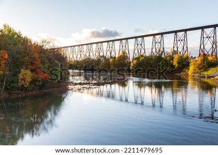 View of the 1908 railway trestle bridge and its reflection in the Cap-Rouge River seen during a fall morning golden hour, Quebec City, Quebec, Canada Royalty-Free Stock Photo #2211479695