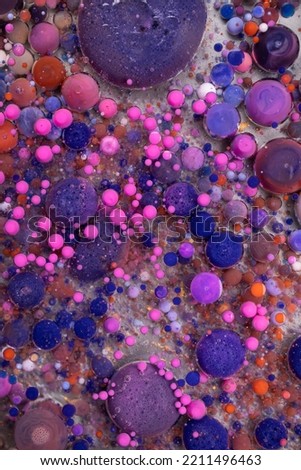 Acrylic paint balls abstract texture. Bright colors fluid, flowing wallpaper design. Purple, blue, pink and yellow liquids mix.