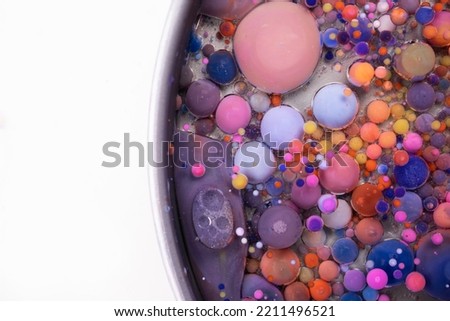 Acrylic paint balls abstract texture. Bright colors fluid, flowing wallpaper design. Purple, blue, pink and yellow liquids mix.