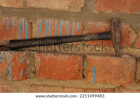 An iron hammer on the background of a red brick wall. Tools for construction and repair