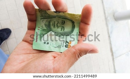 20 Baht banknote out of her purse to pay, holding Thailand paper currency money cash to pay for street food outdoors in the day