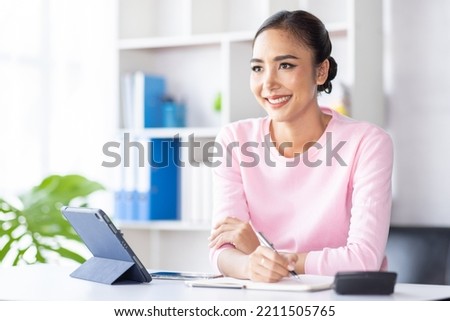 Asian Woman using digital tablet while sitting at home workplace, Asian Female designer sketching on a graphic tablet while working at home.