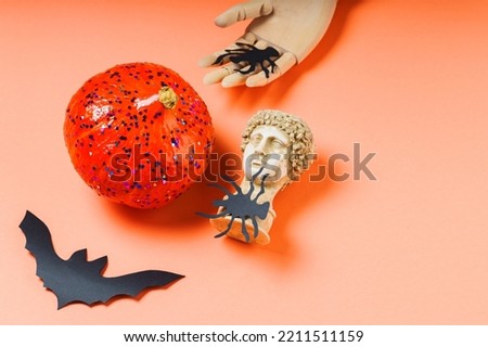 Halloween holiday concept. Glitter pumpkin and party decorations on orange background. Copy space