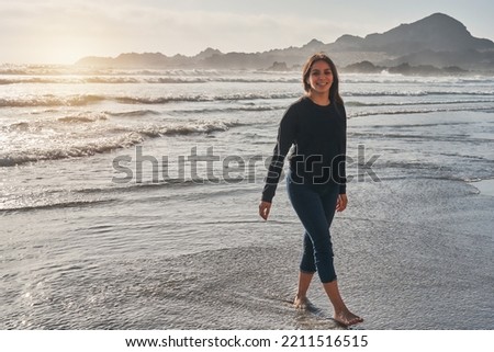 portrait of young latin woman walking along the shore of the beach happy at sunset in Atacama region