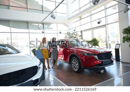 Car dealership manager inspecting a car with a client
