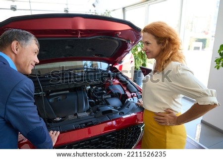 Man and woman are standing near car with open hood