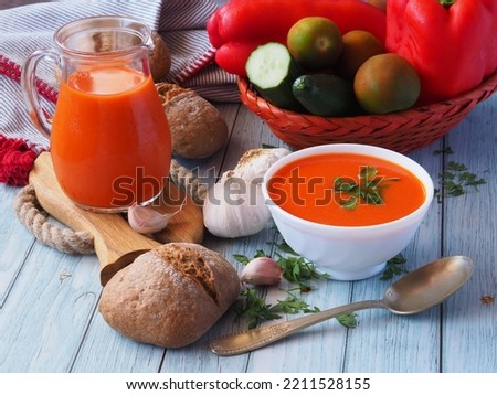 Cold traditional Spanish soup Gazpacho. Composition on a wooden table from a ready-made dish, bread, and fresh vegetables.