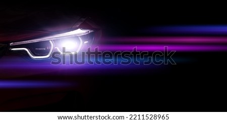 Car headlights with light rays and copy space, banner. Neon purple and blue light of car headlights on a dark background, panorama, close up . Royalty-Free Stock Photo #2211528965