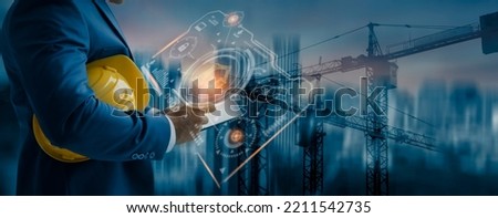 Double exposure engineering using tablet computer and digital technology interfaces icon on construction cranes background, Technology and business industrial concept. Royalty-Free Stock Photo #2211542735