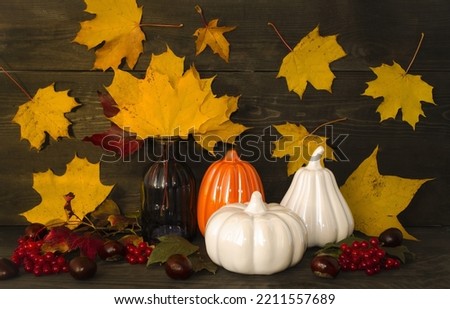 Autumn still life on a wooden background autumn leaves and berries, decorative pumpkins symbol of Halloween.  The concept of decorating houses, apartments on holidays.  Front view.
