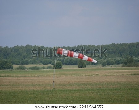 Synthetic product made of red and white fabric. Wind direction and strength indicator on the airfield on a sunny summer day.