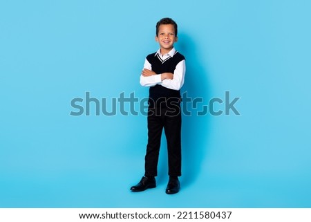 Full length photo of cheerful charming small boy wear black waistcoat smiling arms crossed isolated blue color background Royalty-Free Stock Photo #2211580437