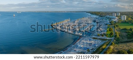 Aerial view of marina Schilksee with sailing boats docked at the pier. Aerial view of popular sailing vacation destination Schilksee with Olympic center with marina on the Baltic Sea. Royalty-Free Stock Photo #2211597979