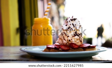 Waffles with ice cream on a plate on a wooden table in an open-air restaurant
