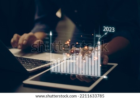 financial charts and graph analysis marketing showing growing revenue In 2023 floating above digital screen tablet, business about strategy for growth and success.