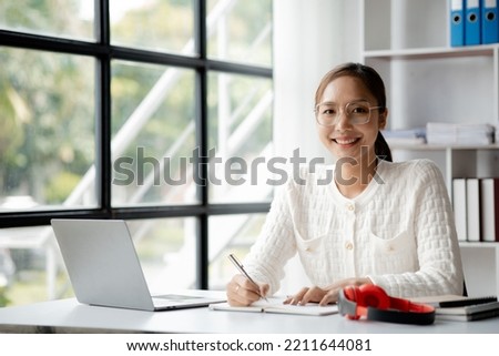 A businesswoman is checking company financial documents and using a tablet to talk to the chief financial officer through a messaging program. Concept of company financial management. Royalty-Free Stock Photo #2211644081