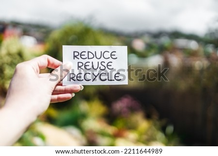 reduce reuse recycle sign in front of backyard bokeh, concept of sustainability and circular economy