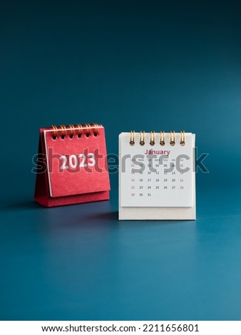 January 2023 calendar desk for the organizer to plan and reminder on blue background, vertical style. White table calendar with the first month near red cover with 2023 year numbers, Happy new year.