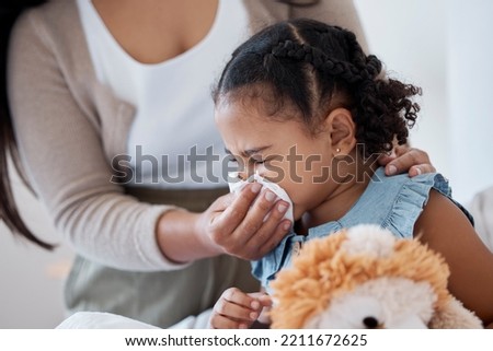 Mother clean sick child nose with tissue, playing with toy or teddy bear in bedroom at family home. Teacher at kindergarten use toilet paper, to help clean young girl face after sneeze or runny nose Royalty-Free Stock Photo #2211672625