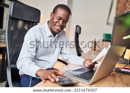 Smiling businessman calculating business income doing paperwork in office Royalty-Free Stock Photo #2211676507