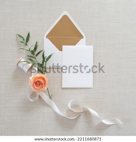 Invitation cards template on gray fabrics background. Workspace with blank paper, rose,ribbon, empty card and white envelope.