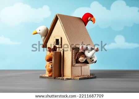 Seven finger puppets come out of a cardboard house craft with blue sky illustration background 