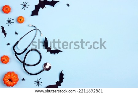 Stethoscope and Halloween decorations on blue background with copy space. Party invitation, Medical Halloween greeting card.