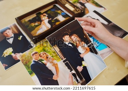 printed wedding photos in the hands and in a wooden box with a flash drive. the concept of preserving the memory of an important event, the services of a professional photographer for the celebration.
