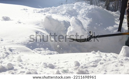 Snow removal with a shovel near the house. Light winter background
