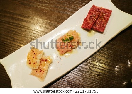 Three different colors and varieties of meat on a long white plate, ingredients for barbecue