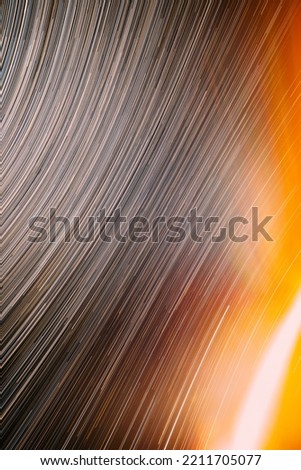 Meteors Trace On Night Dark Blue Sky Background. Spin Of Unusual Amazing Stars Effect In Sky. Abstract Bewitching Illusion Of Star Trails. Trace Of Sun. Saturated Bright Yellow, Orange Colors.