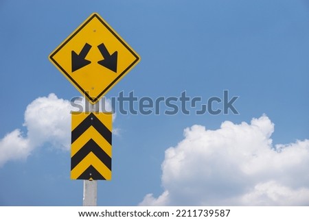 Yellow traffic sign with symbol of two arrows  for the two way run.  to warn drivers be careful  Concept : Warning traffic sign for transportation. Blue sky scene.                             