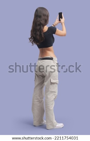 Young beautiful woman taking pictures with her smartphone, back view Royalty-Free Stock Photo #2211754031