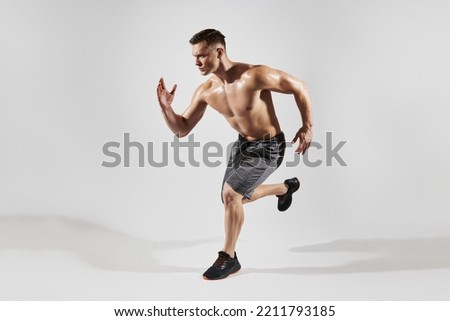 Handsome muscular man with perfect torso running against white background