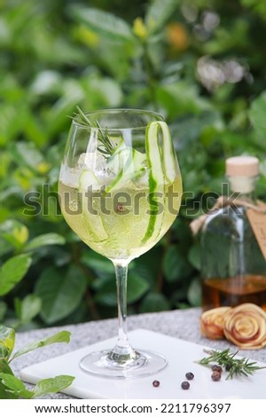Cucumber and rosemary Mixed Herbal Drink cocktail in red wine glass. Cordial and herbs with Garden background Royalty-Free Stock Photo #2211796397