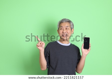The 40s adult Asian man with casual shirt standing on the green background.