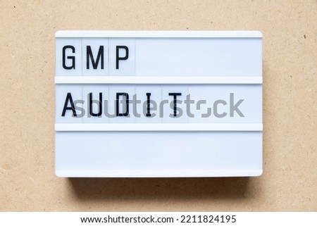 Lightbox with word GMP (Good manufacturing practice) audit on wood background