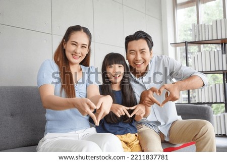 Happy Asian family making mini heart symbol in living room. Family,love and happiness concept.