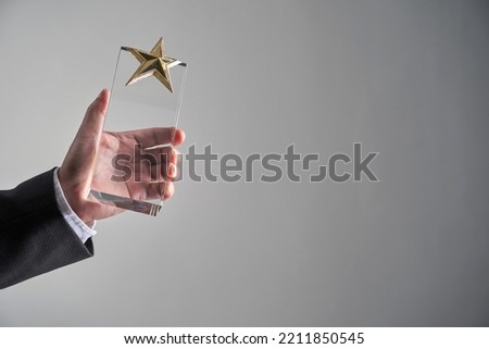 close up of hand holding star shape glass trophy                   
