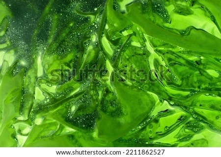 Acidic green liquid. Abstract background with light green slurry with bubbles. Background with stains and streaks. The problem of ecology and environmental pollution.
